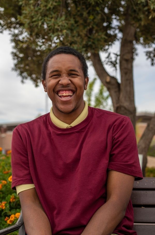 Young man with learning difficulties sitting on a park bench